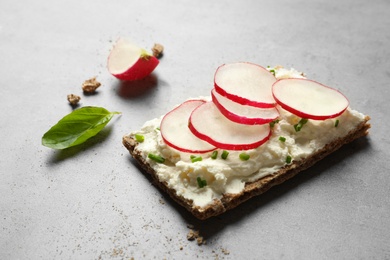 Photo of Tasty snack with cream cheese and radish on gray table