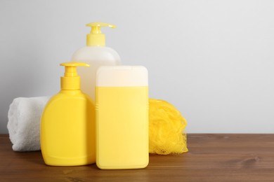 Photo of Different shower gel bottles with pouf and towel on wooden table. Space for text