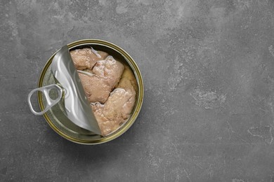 Photo of Open tin can of tasty cod liver on grey table, top view. Space for text