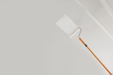 Photo of Painting ceiling with white dye indoors, low angle view. Space for text