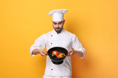 Photo of Surprised chef holding colander on yellow background