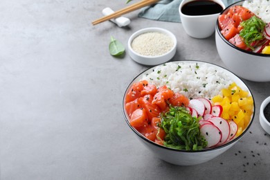 Photo of Delicious poke bowl with salmon and vegetables served on light grey table. Space for text
