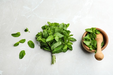 Fresh mint with mortar and pestle on grey marble background, flat lay