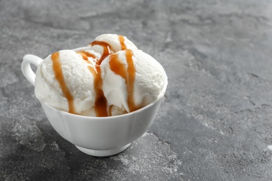 Tasty ice cream with caramel sauce in mug on table