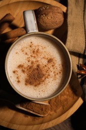 Cup of delicious eggnog with spices on wooden table, top view