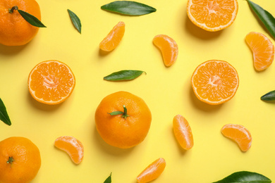 Flat lay composition with fresh ripe tangerines and leaves on light yellow background. Citrus fruit