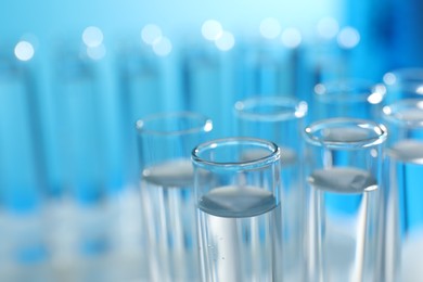 Many glass test tubes on light blue background, closeup