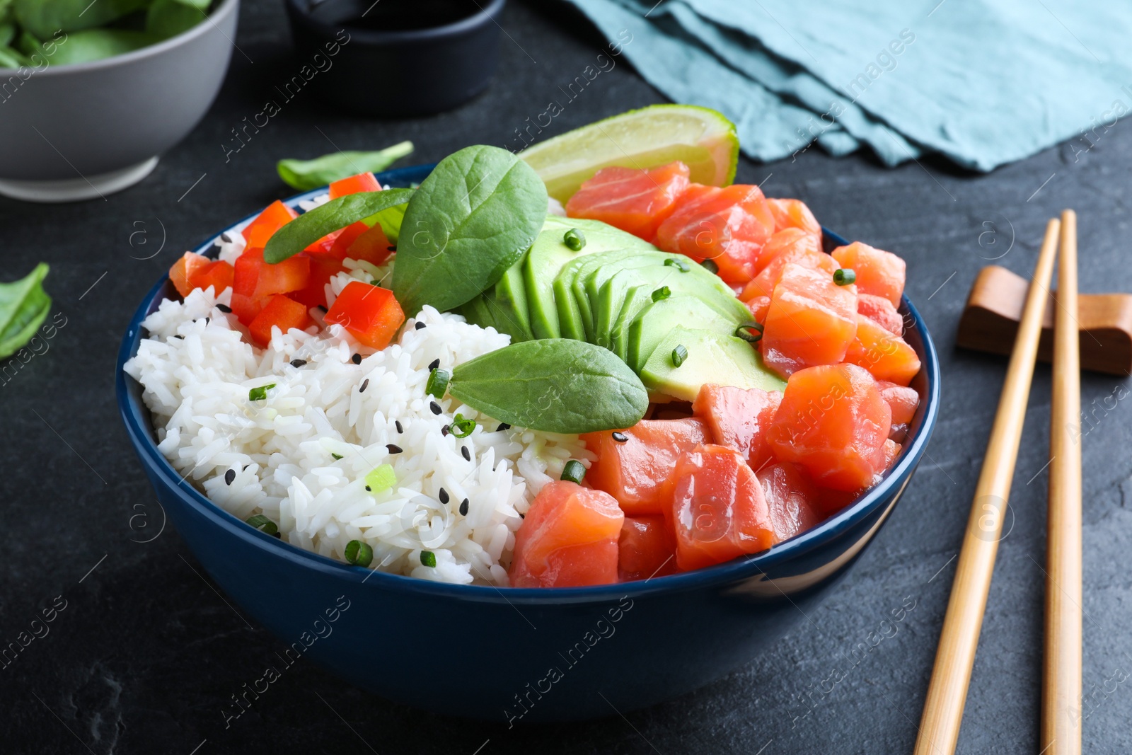 Photo of Delicious poke bowl with salmon, spinach and avocado served on black table