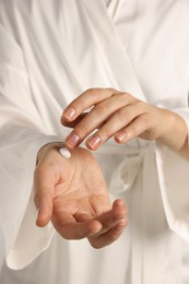 Photo of Woman applying cosmetic cream onto hand, closeup view