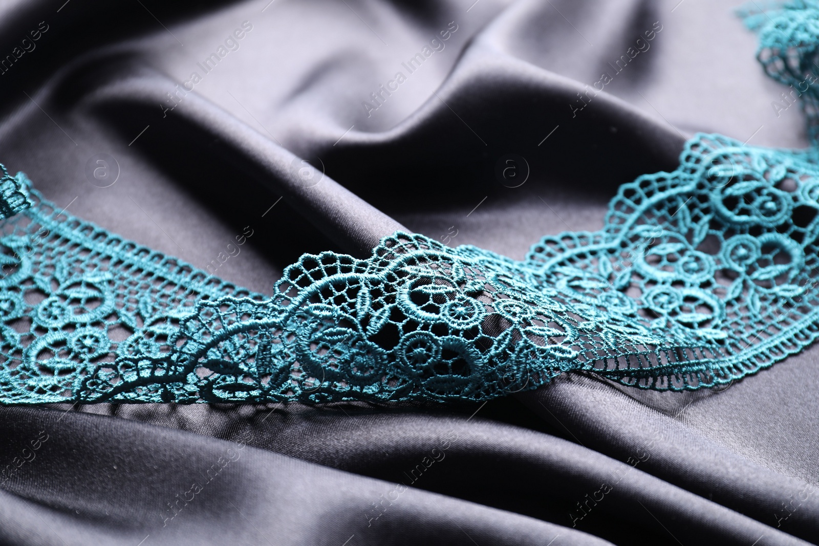 Photo of Beautiful green lace on black fabric, closeup