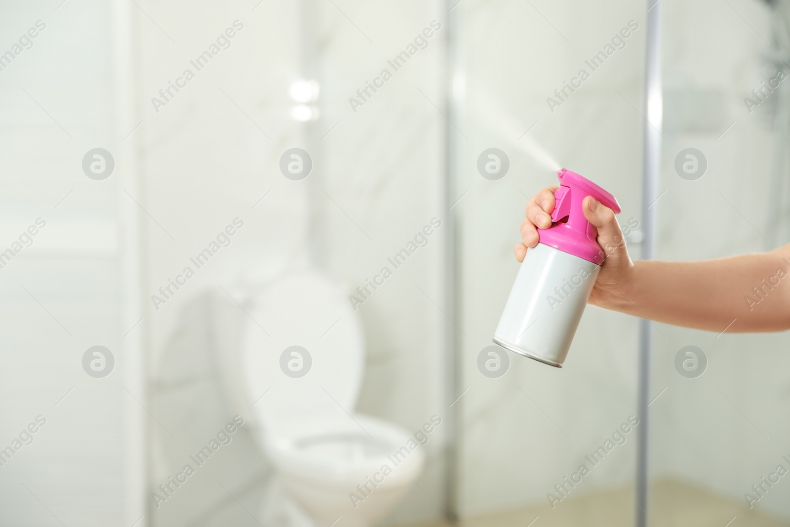 Photo of Woman spraying air freshener in bathroom, closeup