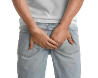 Man suffering from hemorrhoid on white background, closeup