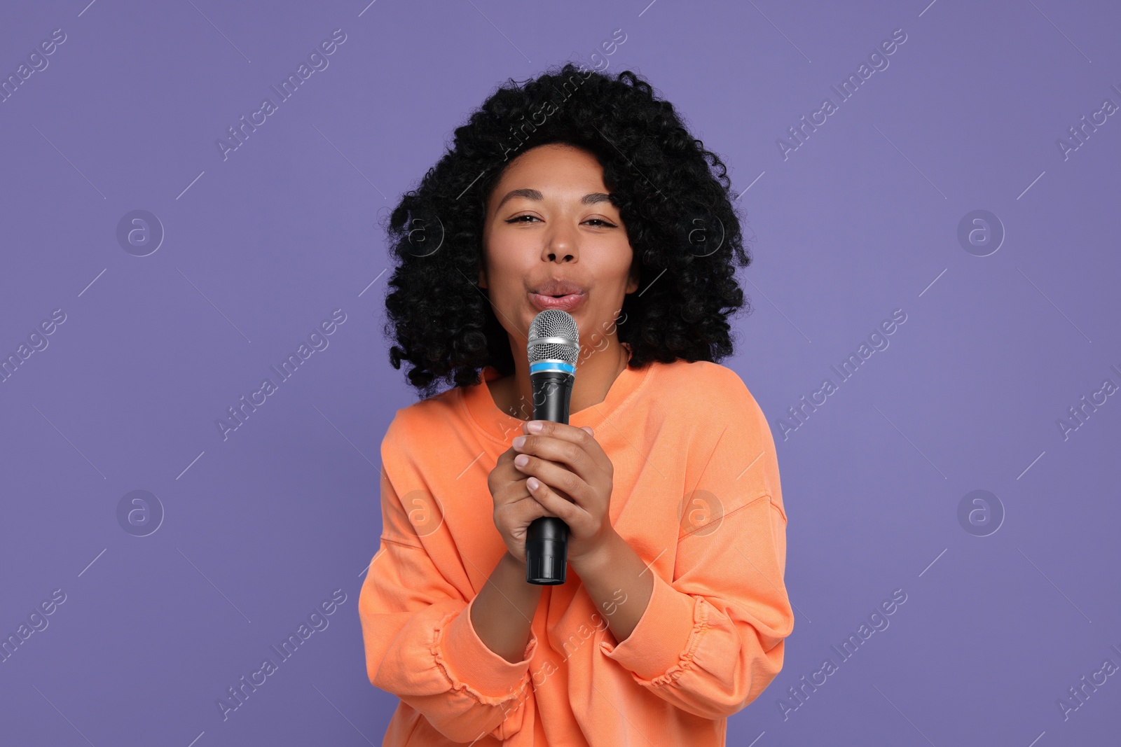 Photo of Beautiful woman with microphone singing on violet background