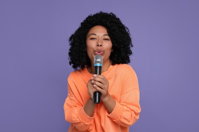 Photo of Beautiful woman with microphone singing on violet background