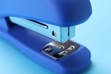 Photo of Bright stapler on light blue background, closeup