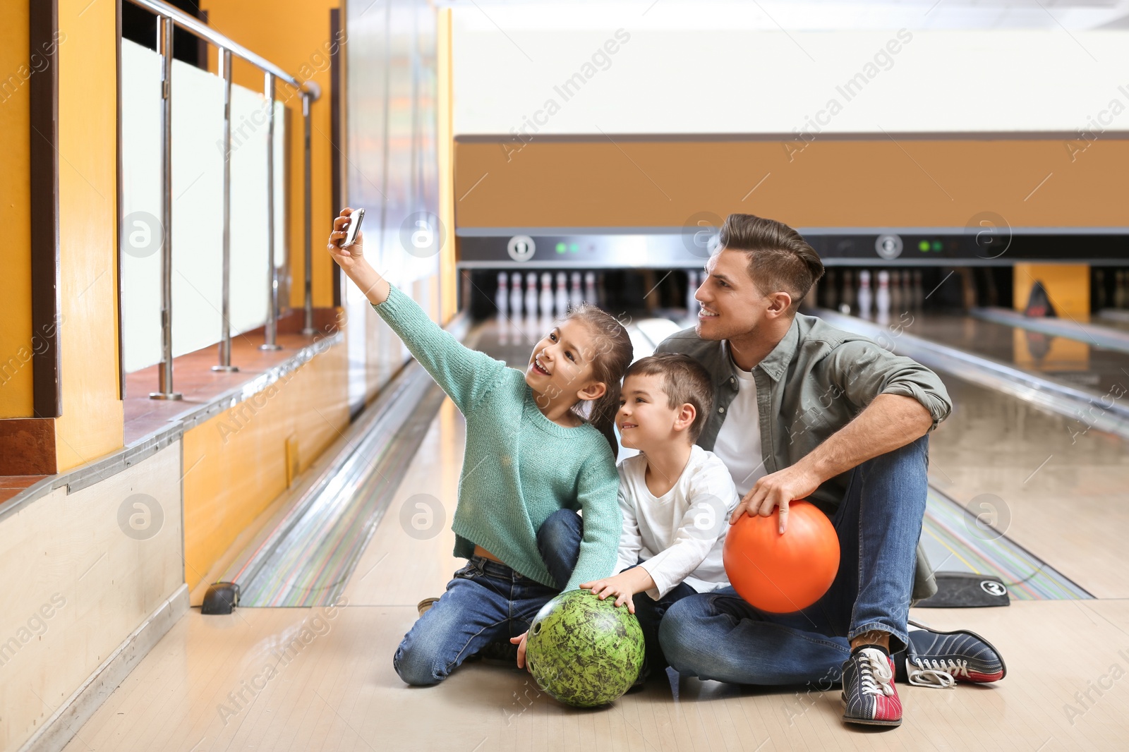 Photo of Happy family taking selfie in bowling club