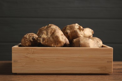 Photo of Crate with fresh Jerusalem artichokes on wooden table