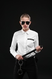 Female security guard with police baton on dark background