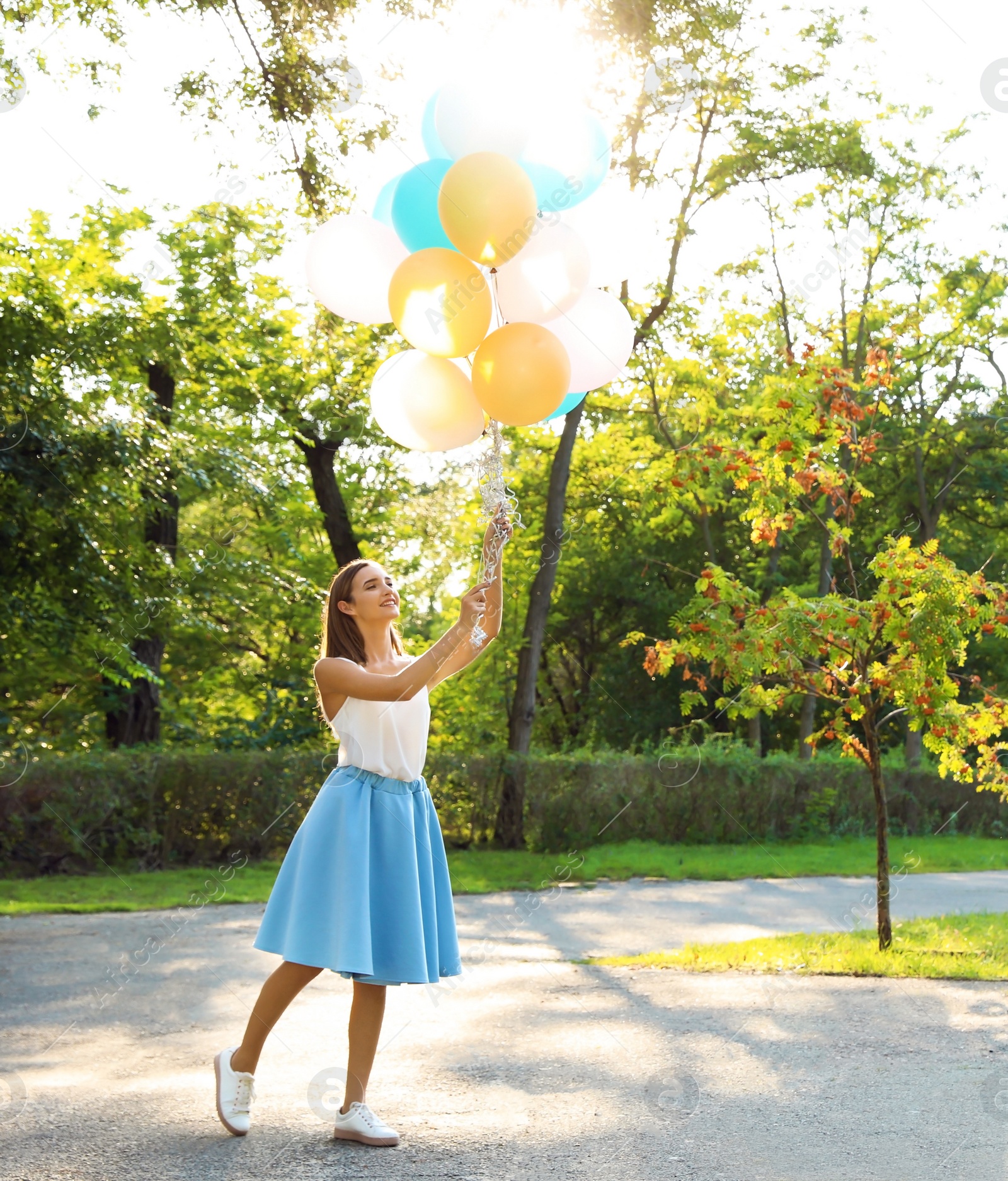 Photo of Beautiful teenage girl holding colorful balloons in park