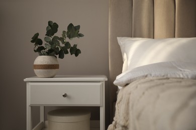 Photo of Vase with beautiful eucalyptus branches on nightstand in bedroom