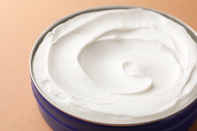 Jar of face cream on beige background, closeup