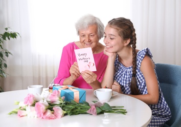 Photo of Preteen girl congratulating her granny at home. Happy Mother's Day