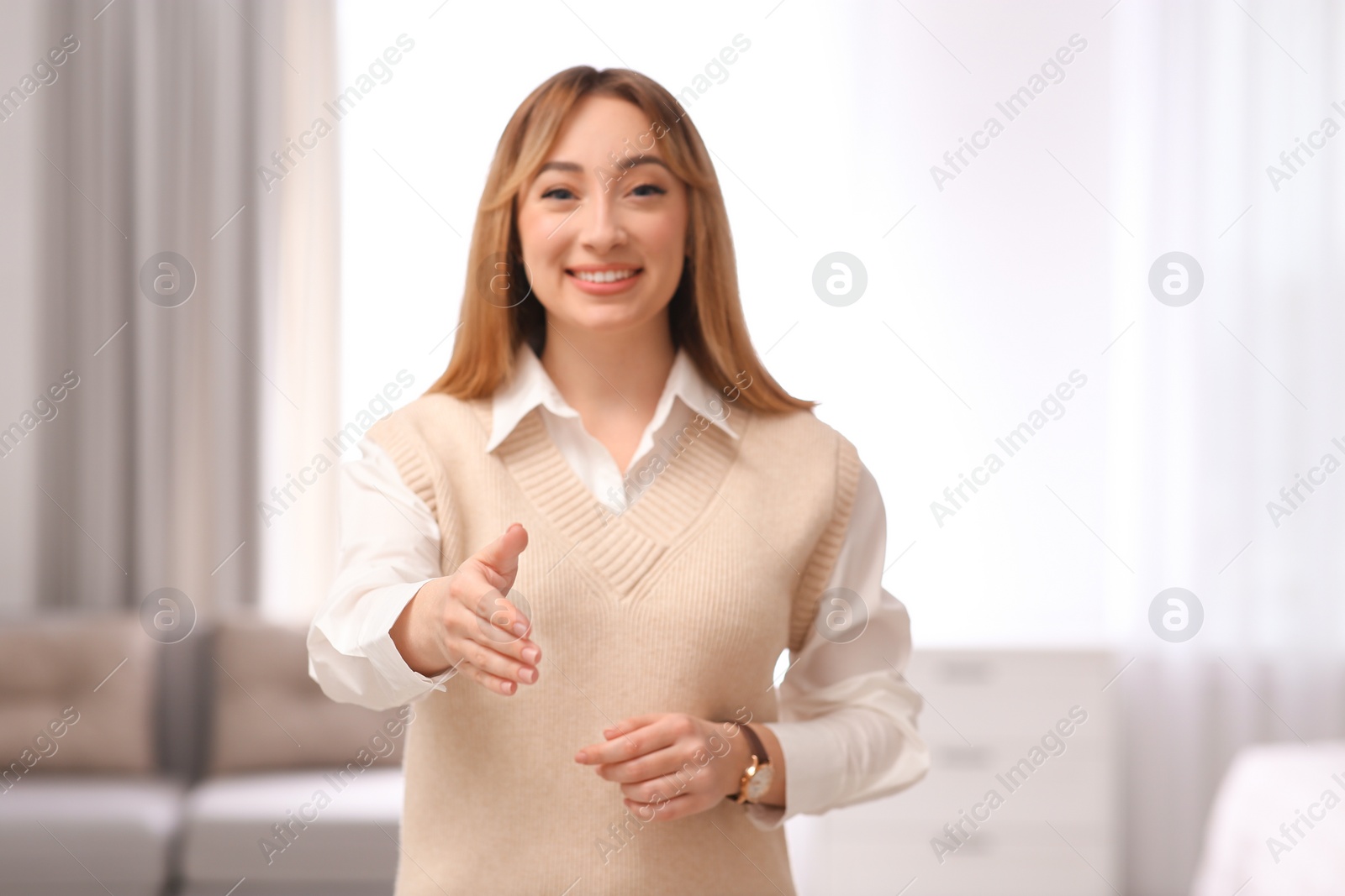 Photo of Happy young woman offering handshake in room