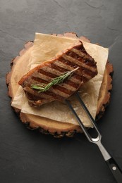 Photo of Delicious grilled beef steak and rosemary on dark gray table, top view
