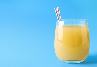 Photo of Glass of delicious juice on light blue background, space for text