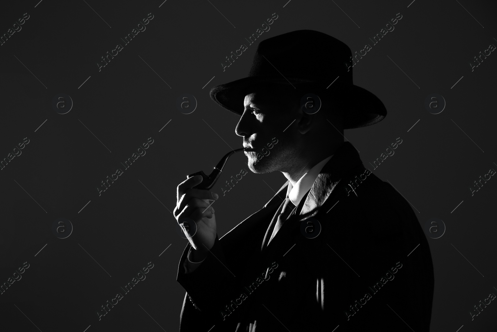 Photo of Old fashioned detective with smoking pipe on dark background, black and white effect