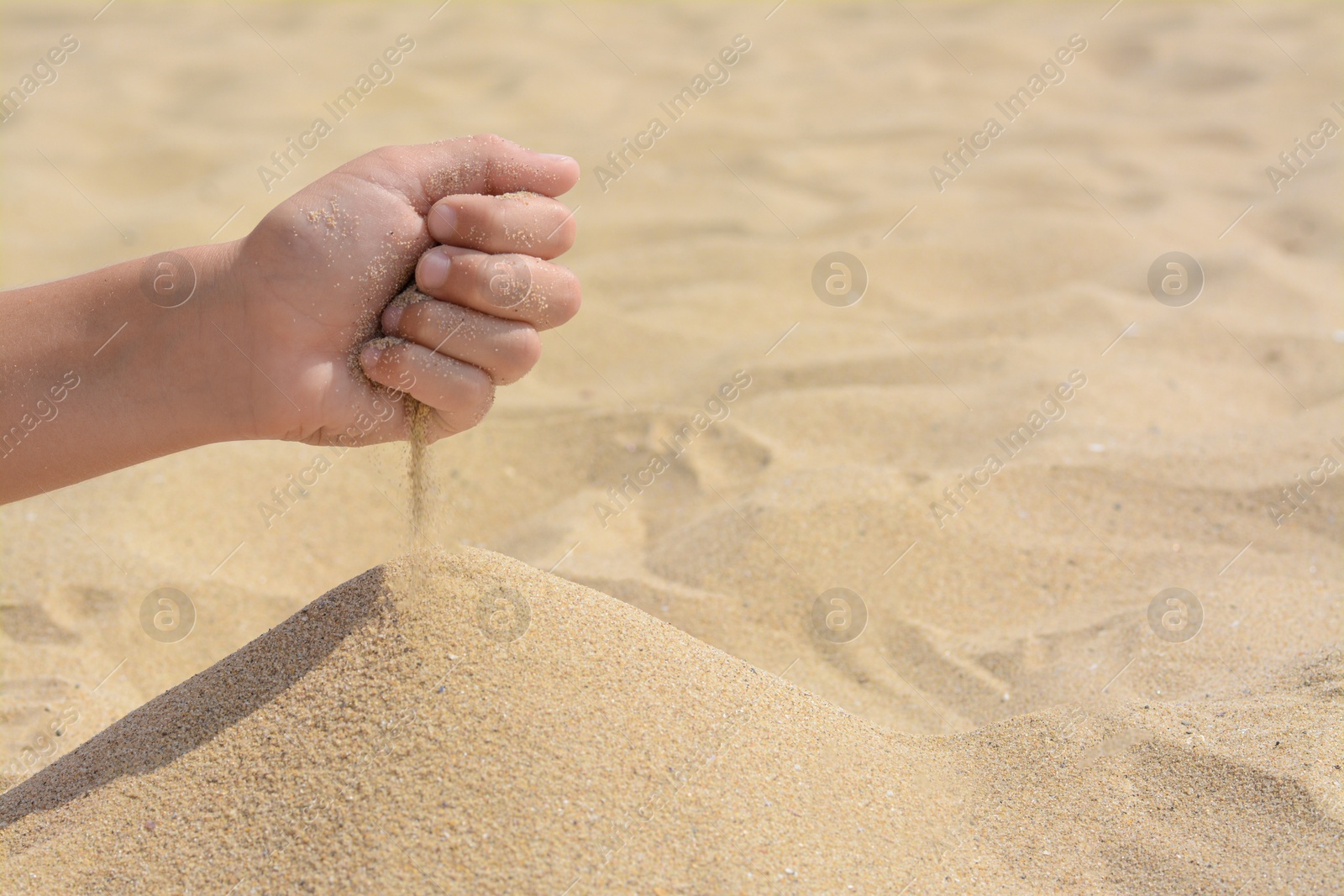 Photo of Child pouring sand from hand on beach, closeup with space for text. Fleeting time concept
