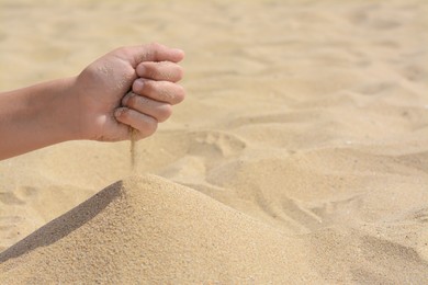 Photo of Child pouring sand from hand on beach, closeup with space for text. Fleeting time concept