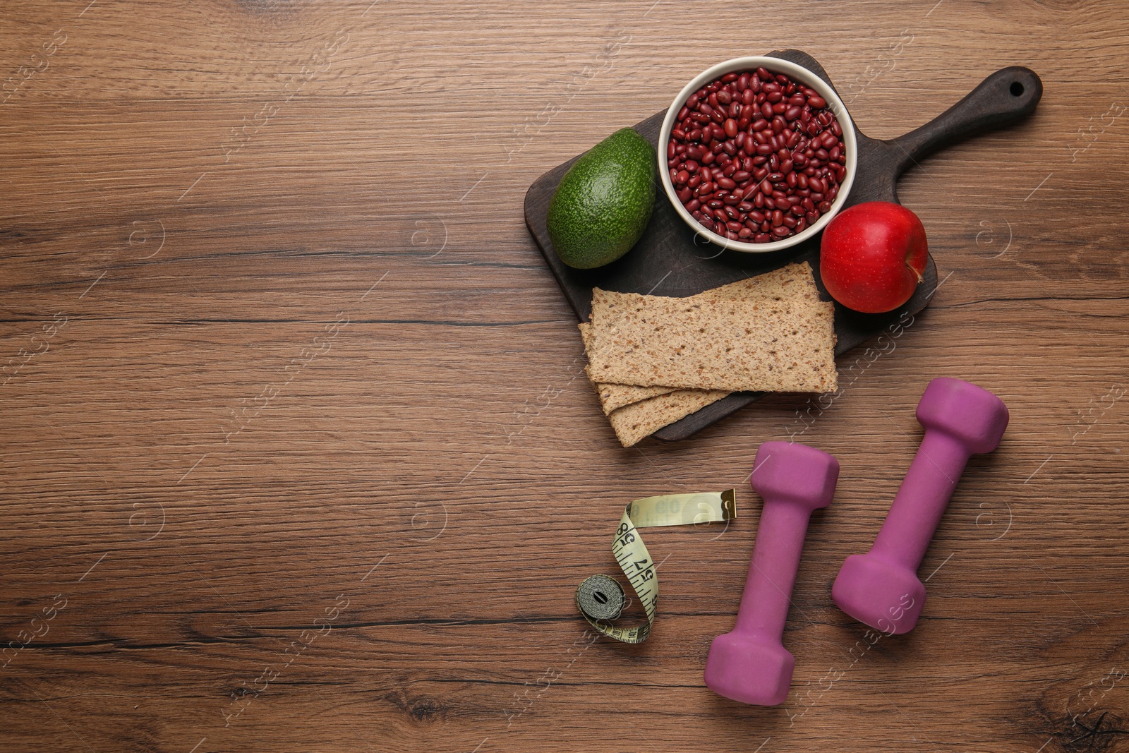 Photo of Healthy diet. Measuring tape, dumbbells and products on wooden table, flat lay. Space for text