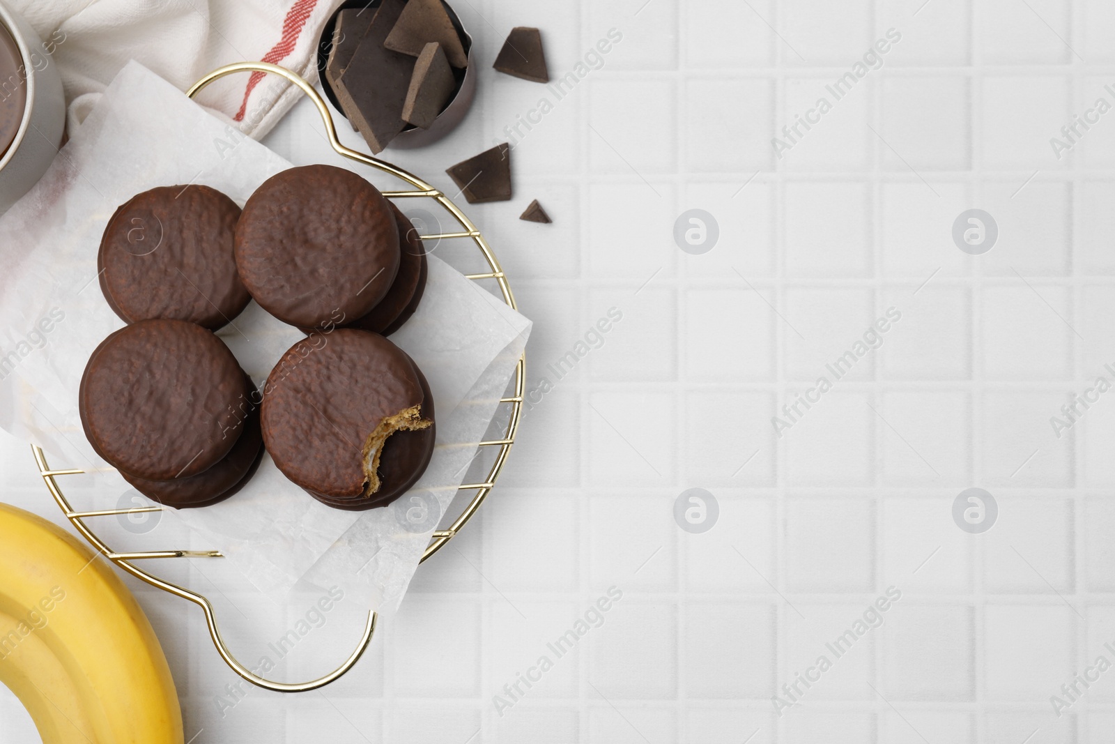 Photo of Tasty banana choco pies, pieces of chocolate and fruits on white tiled table, flat lay. Space for text