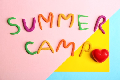 Photo of Words SUMMER CAMP made from modelling clay and small red heart on color background, top view