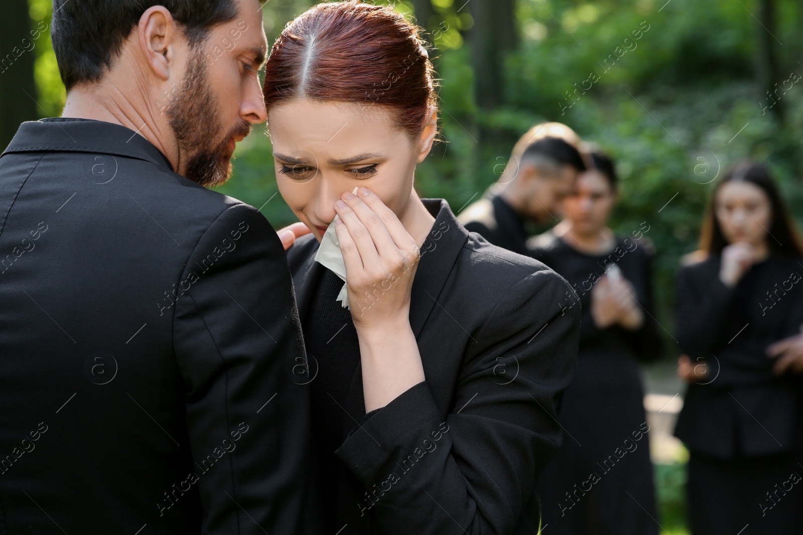 Photo of Sad people in black clothes mourning outdoors. Funeral ceremony