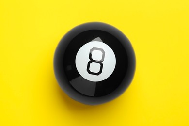 Photo of One magic eight ball on yellow background, top view