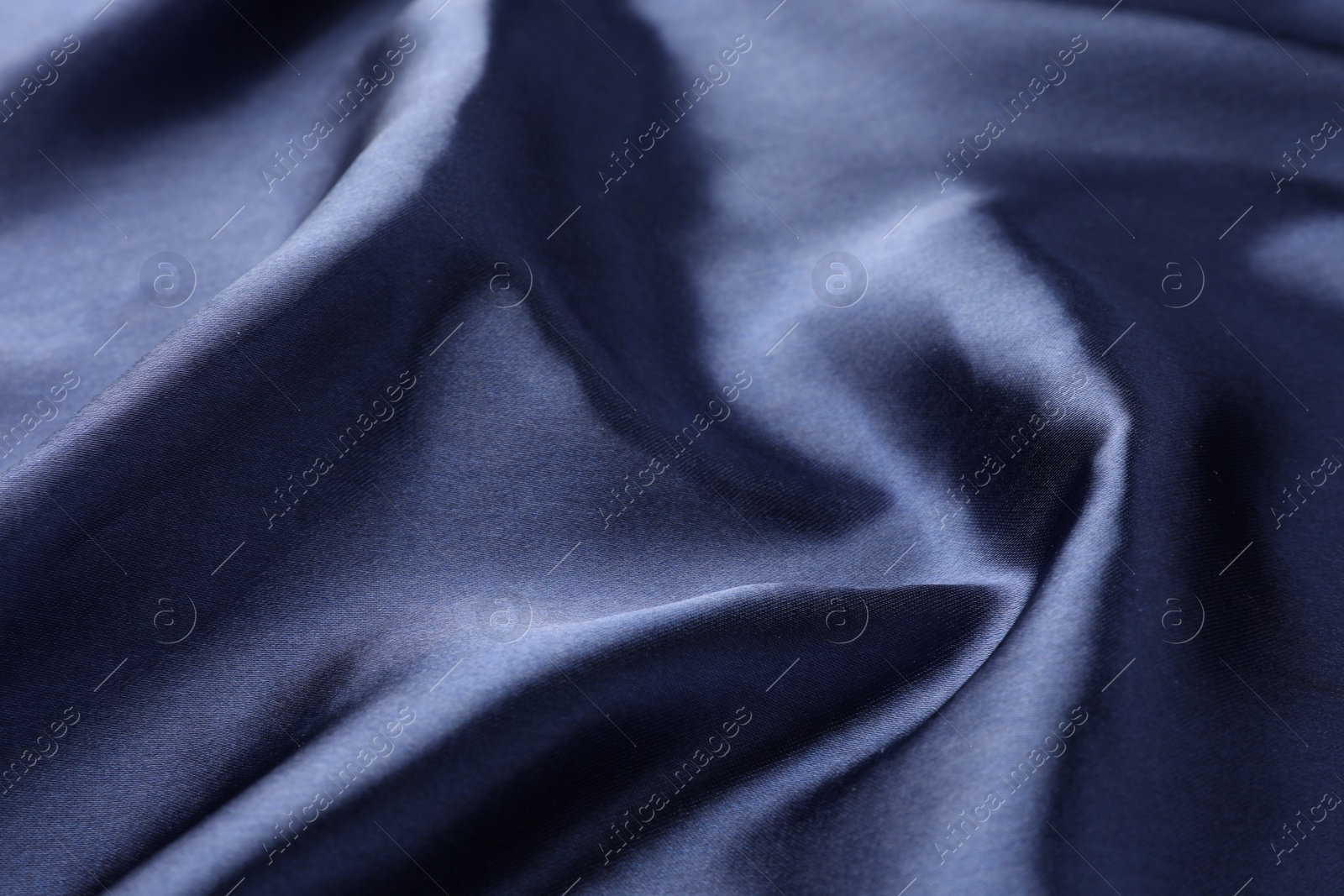 Photo of Crumpled dark blue silk fabric as background, closeup