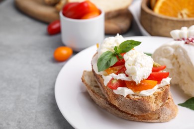Photo of Delicious sandwich with burrata cheese and tomatoes on grey table, closeup. Space for text