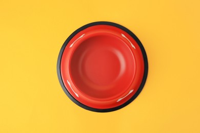 Empty red feeding bowl on orange background, top view