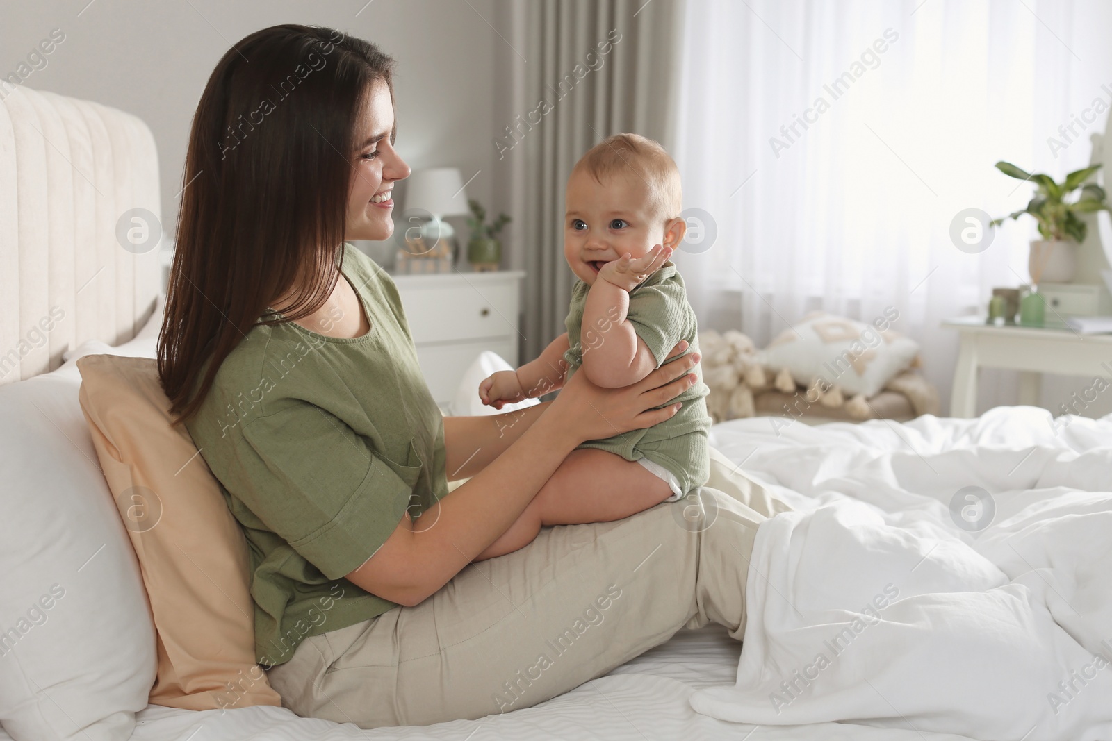 Photo of Happy young mother with her cute baby on bed at home