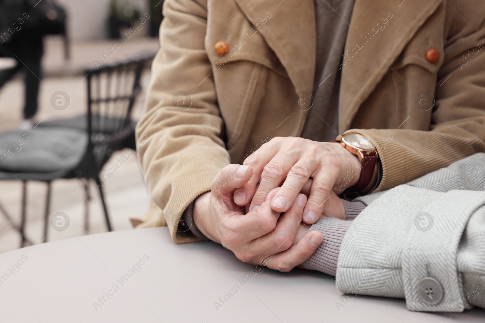 Photo of Affectionate senior couple sitting at table in outdoor cafe, closeup