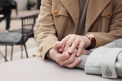 Affectionate senior couple sitting at table in outdoor cafe, closeup
