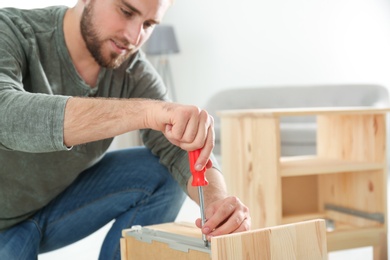 Photo of Young working man repairing drawer at home, space for text