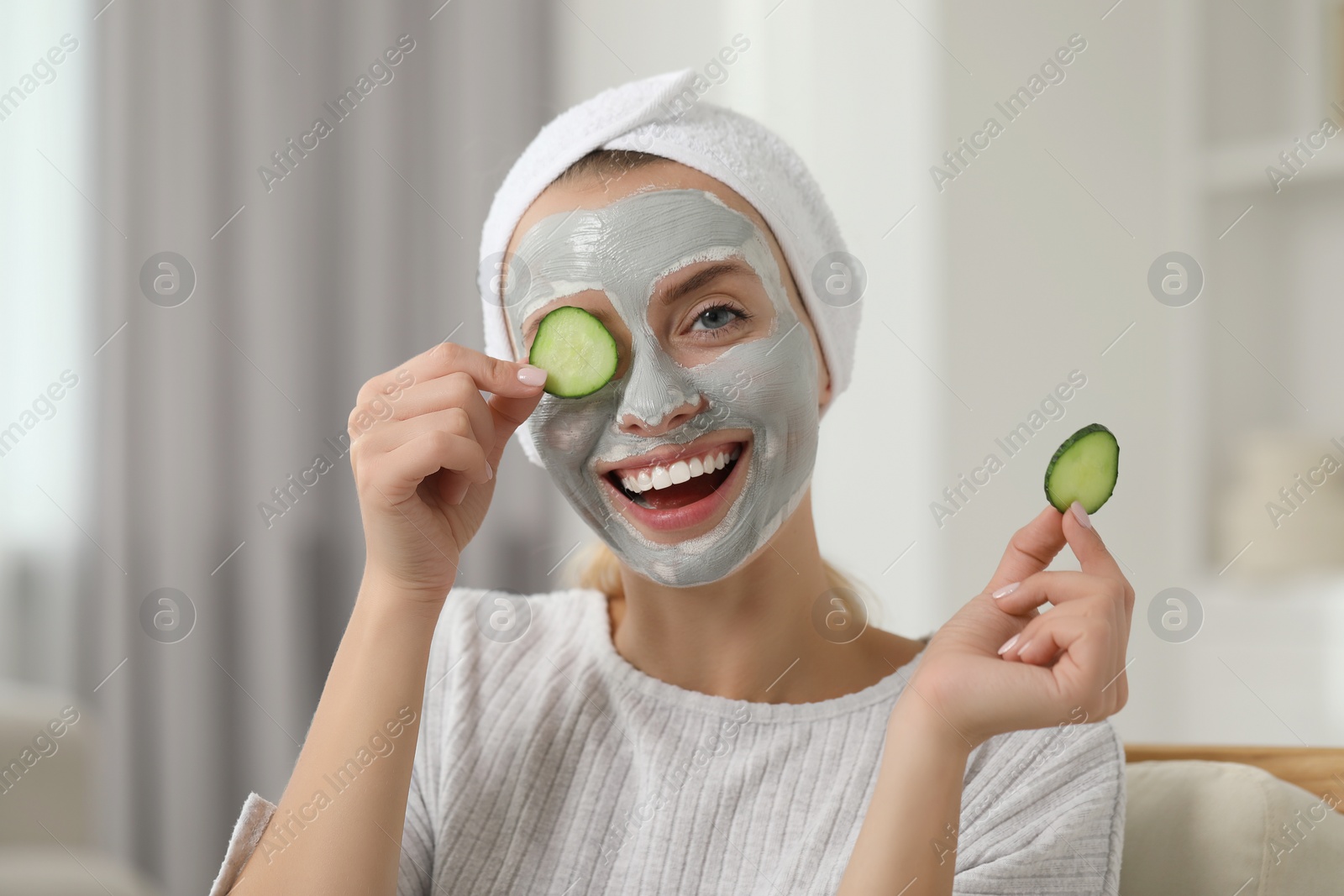 Photo of Young woman with face mask and cucumber slices at home. Spa treatments