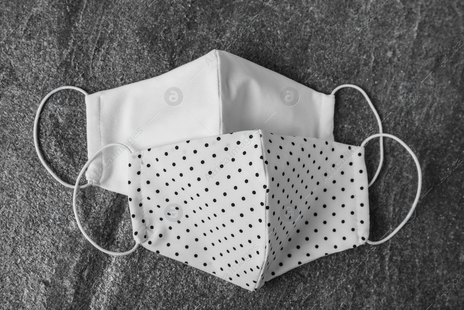 Photo of Homemade protective face masks on grey stone table, flat lay