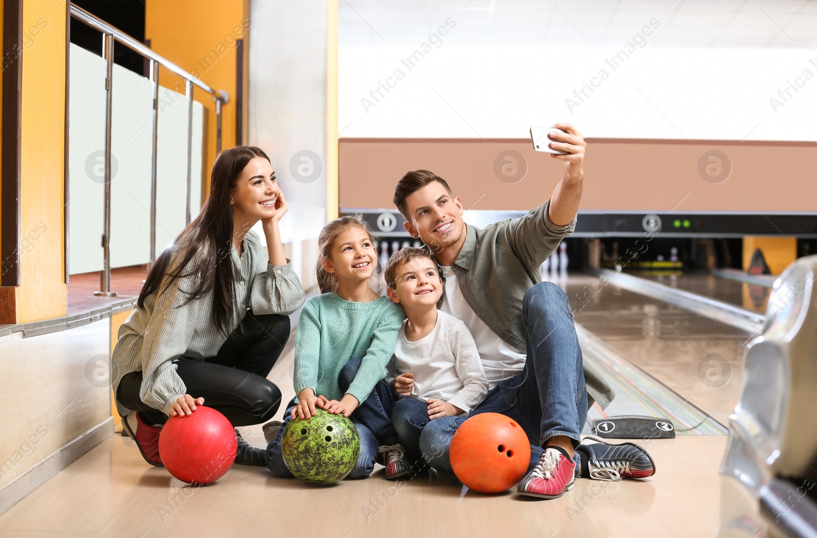 Photo of Happy family taking selfie in bowling club