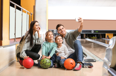 Photo of Happy family taking selfie in bowling club