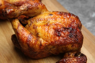 Delicious grilled whole chicken on wooden board, closeup