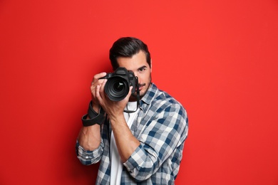 Photo of Young professional photographer taking picture on red background